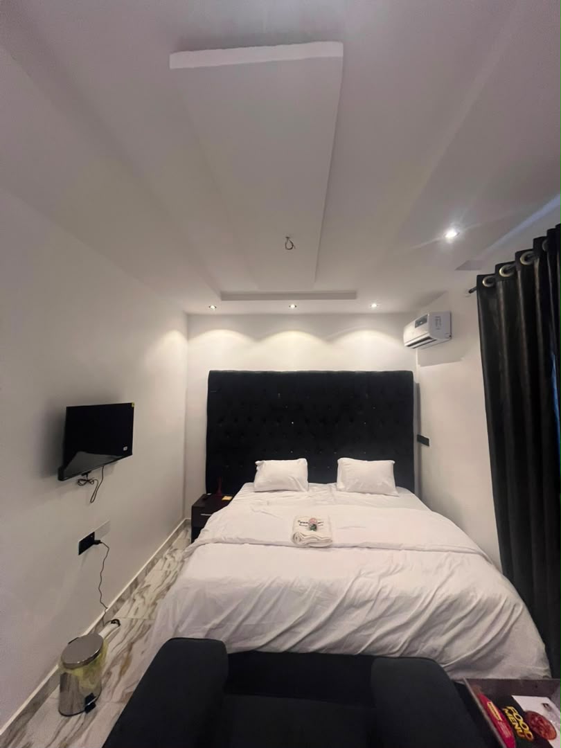 Compact room with tufted black headboard and wall-mounted TV